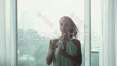 迷人的年轻女孩睡衣在气窗的背景上喷着一股香水的香味